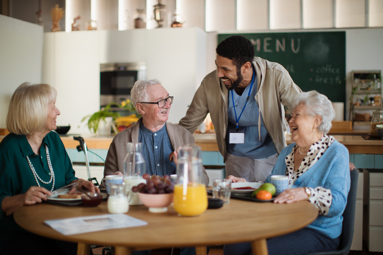Care team member engaging warmly with residents during mealtime at Gables of Ojai