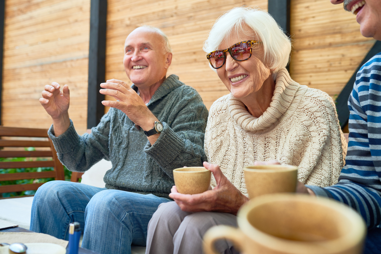 Happy seniors enjoying coffee and conversation outdoors at Gables of Ojai